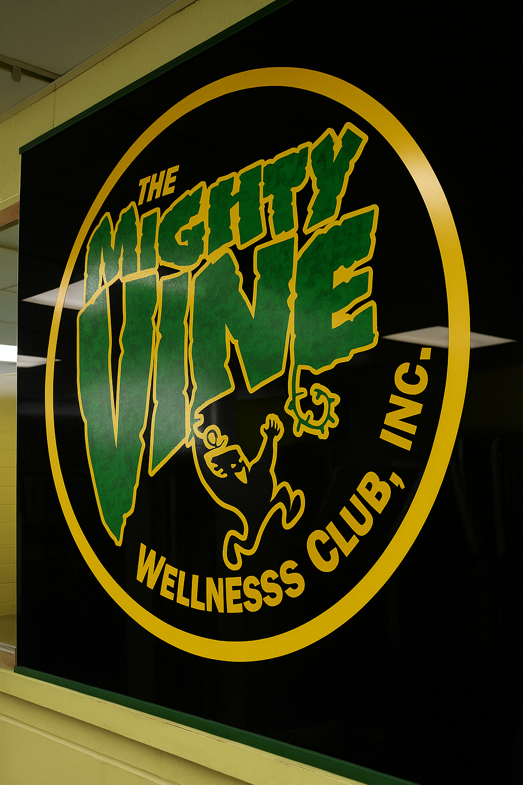 Large Mighty Vine Wellness Club logo on a black wall